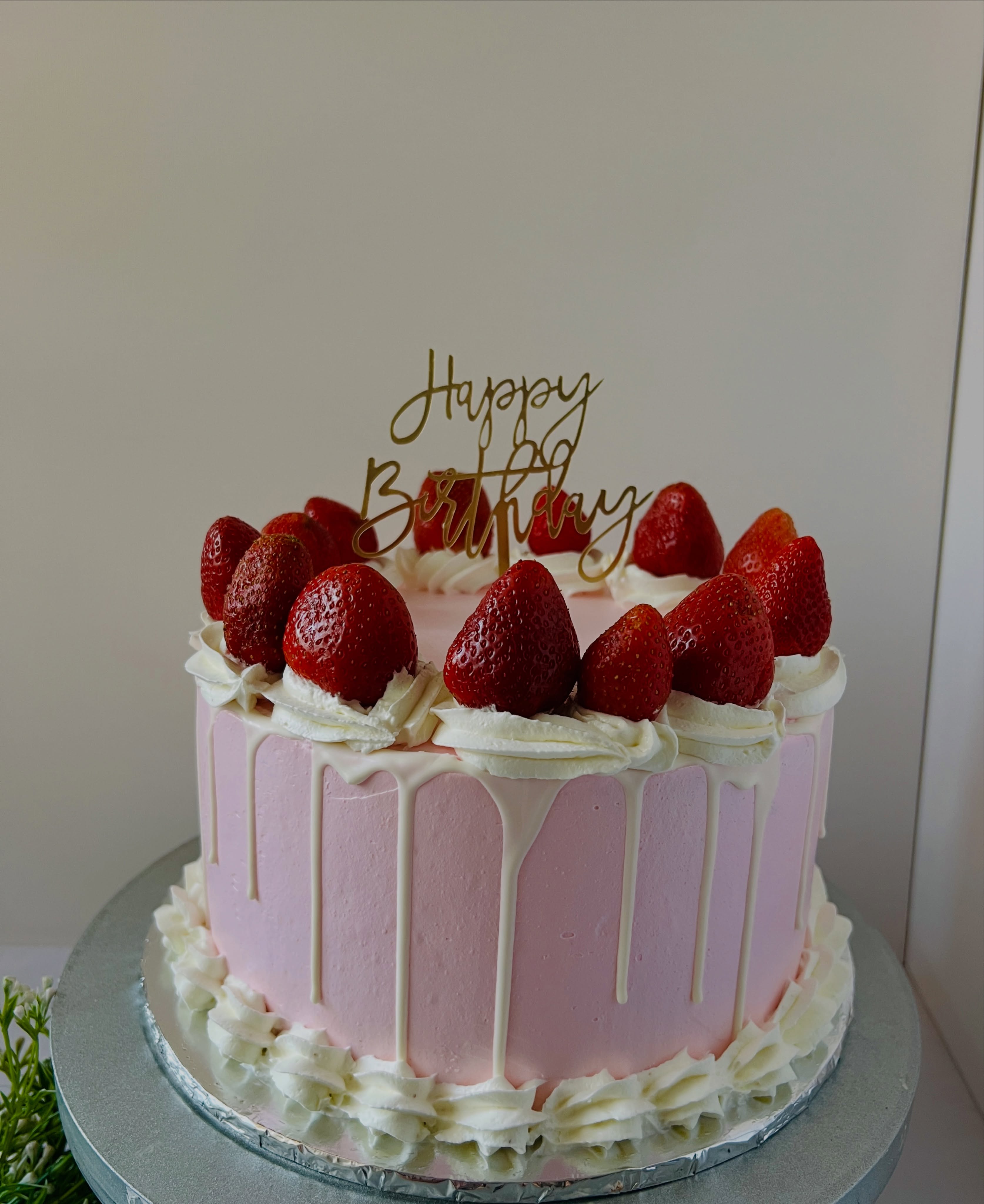 Pink celebration cake with strawberries and white chocolate drip